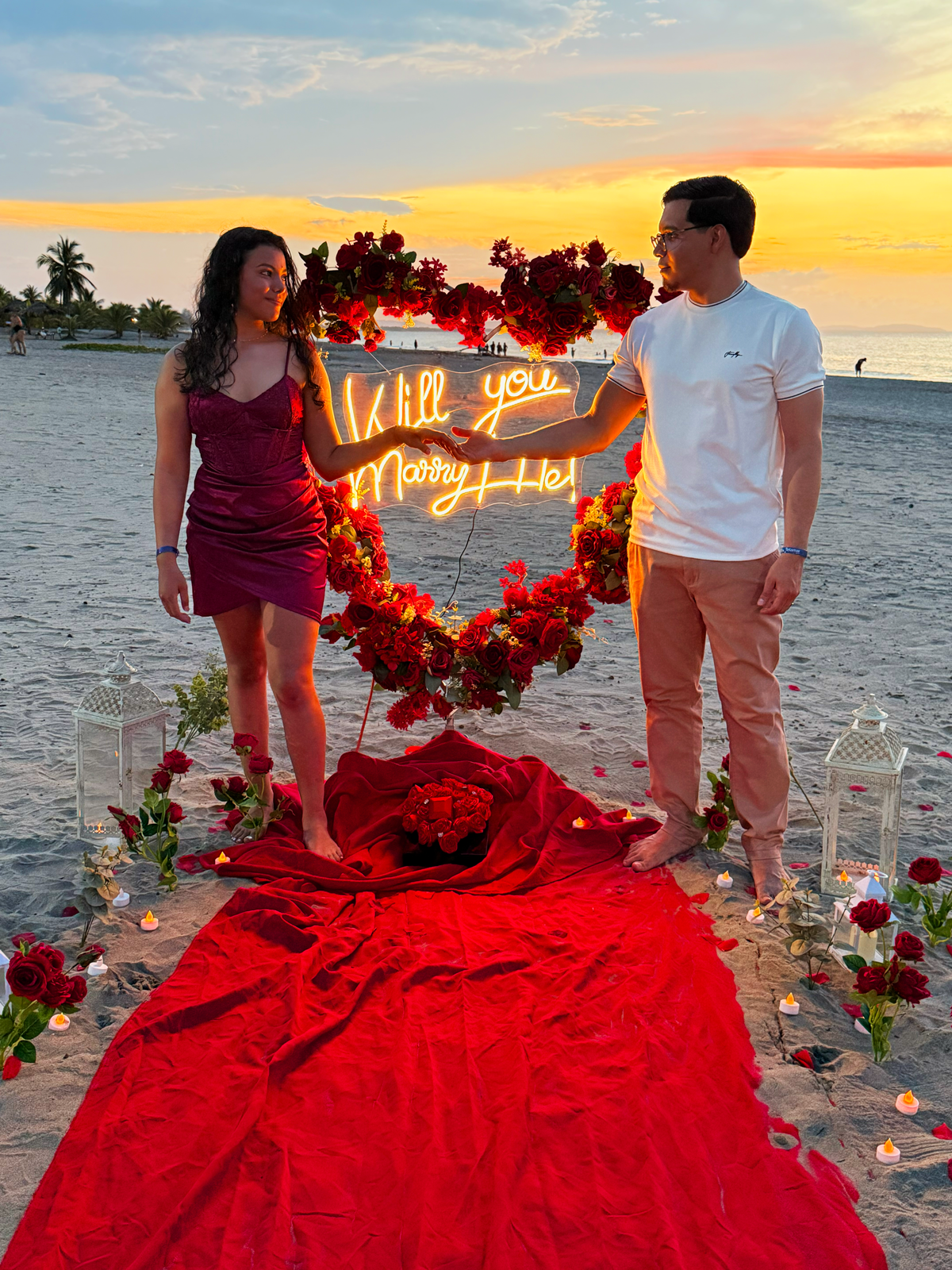 Harold y Allison junto a un corazón de flores rojas